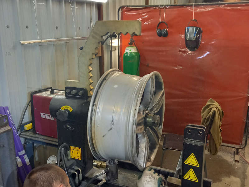 An alloy wheel being straightened back to true on a workshop wheel straightening machine